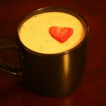 Strawberry milk in a dark cup garnished with a freeze-dried strawberry