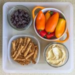Healthy work snacks dried cherries, sweet peppers, hummus, tortilla chips