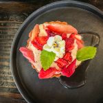 A round black plate with a strawberry rhubarb tart