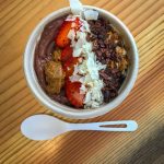 A small smoothie bowl photographed from the top down covered in cacao nibs, strawberries and coconut