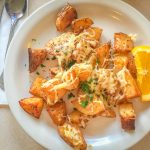 White plate covered with roasted potatoes and melted white cheese