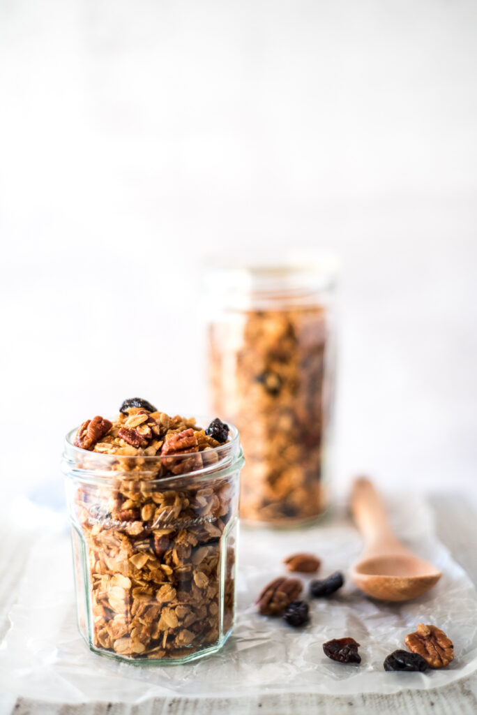 Two jars of granola on a board with a spoon