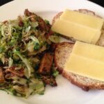 Plate with tofu and brussels sprouts next to bread with cheese