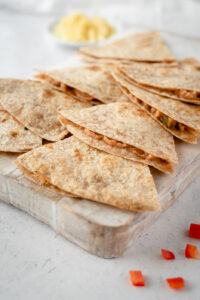 Quesadillas lined up on a cutting board