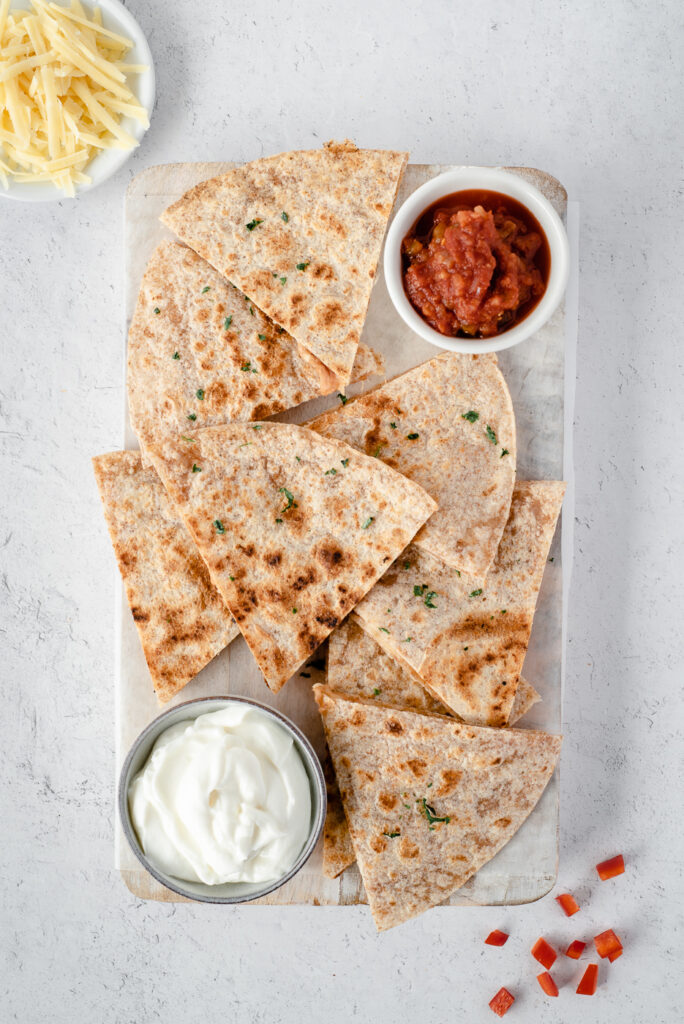 Top down view of a cutting board covered with quesadilla triangles