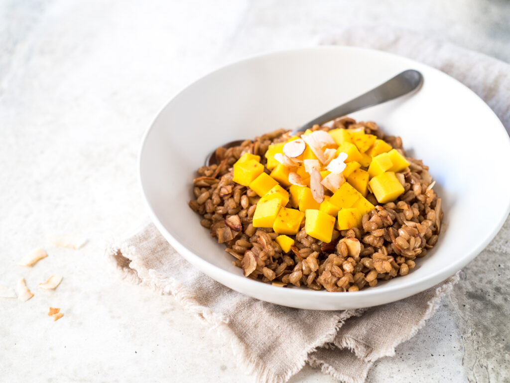Bowl of cooked barley topped with mango
