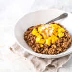 Bowl of cooked barley topped with mango