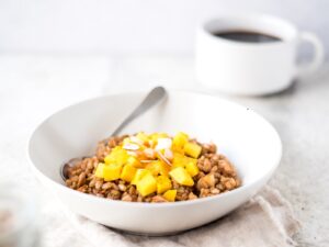 Bowl of cooked barley next to a cup of coffee