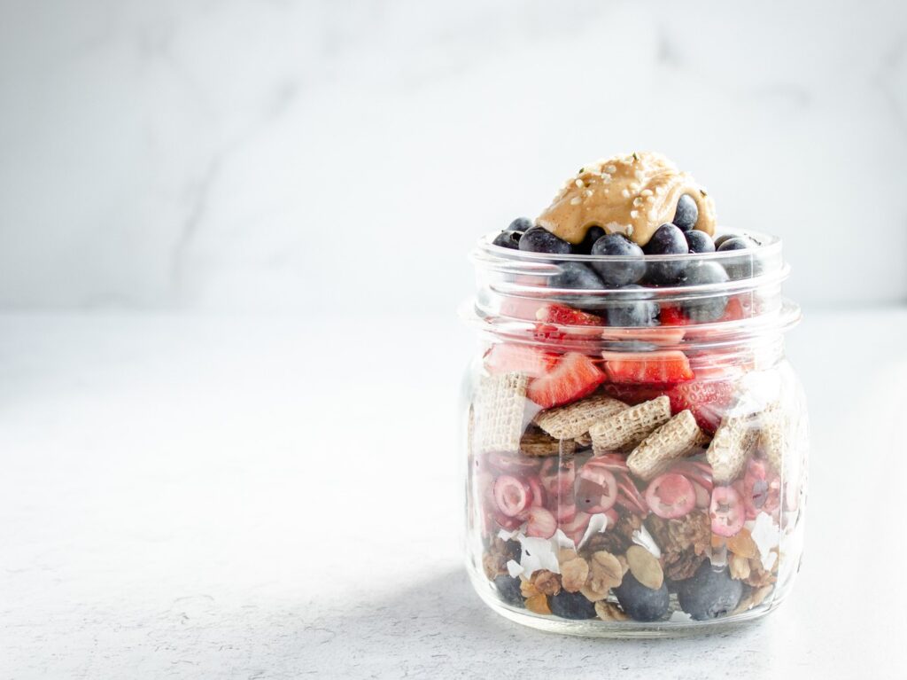 mason jar filled with coconut, fruit, cereal and peanut butter