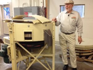 A man standing next to an industrial grain mill