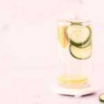 Glass of water with lemon, cucumber and orange slices in it
