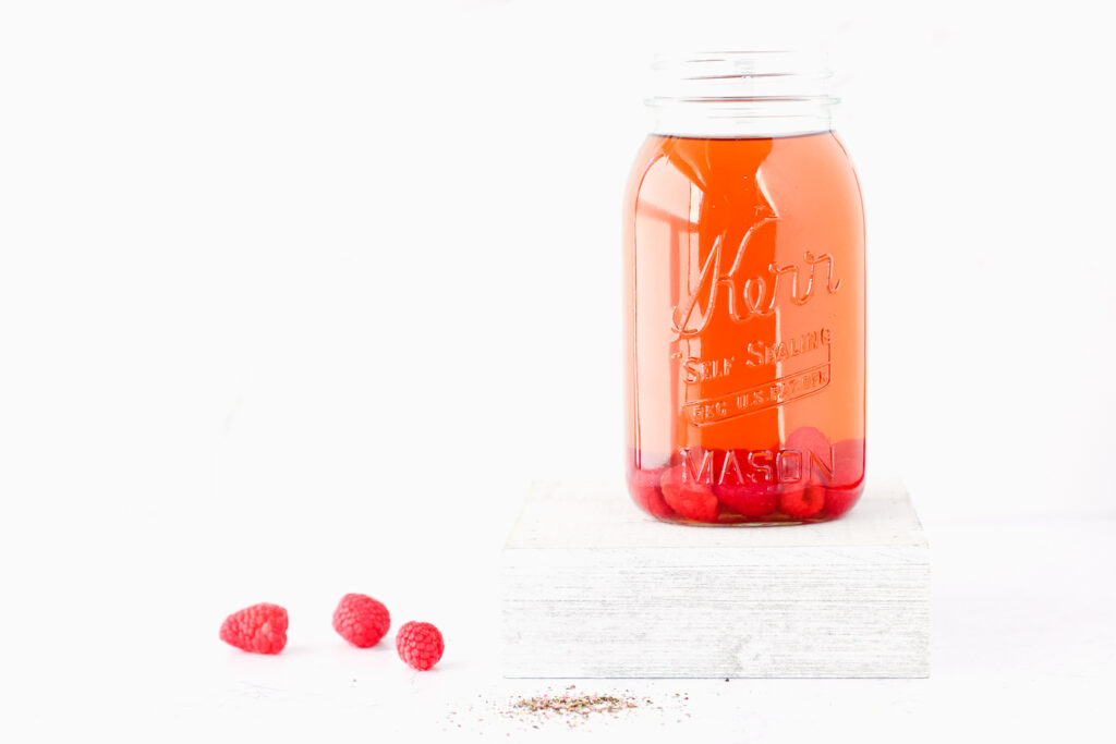 Mason jar of iced tea with raspberries in it