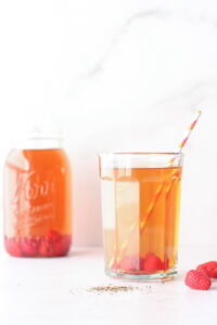 Glass of iced tea with raspberries in it and a mason jar of iced tea