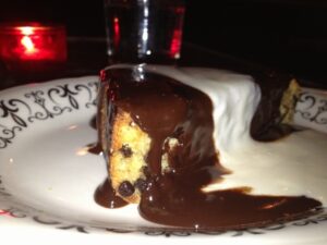 Piece of chocolate chip cake on a plate covered with chocolate sauce