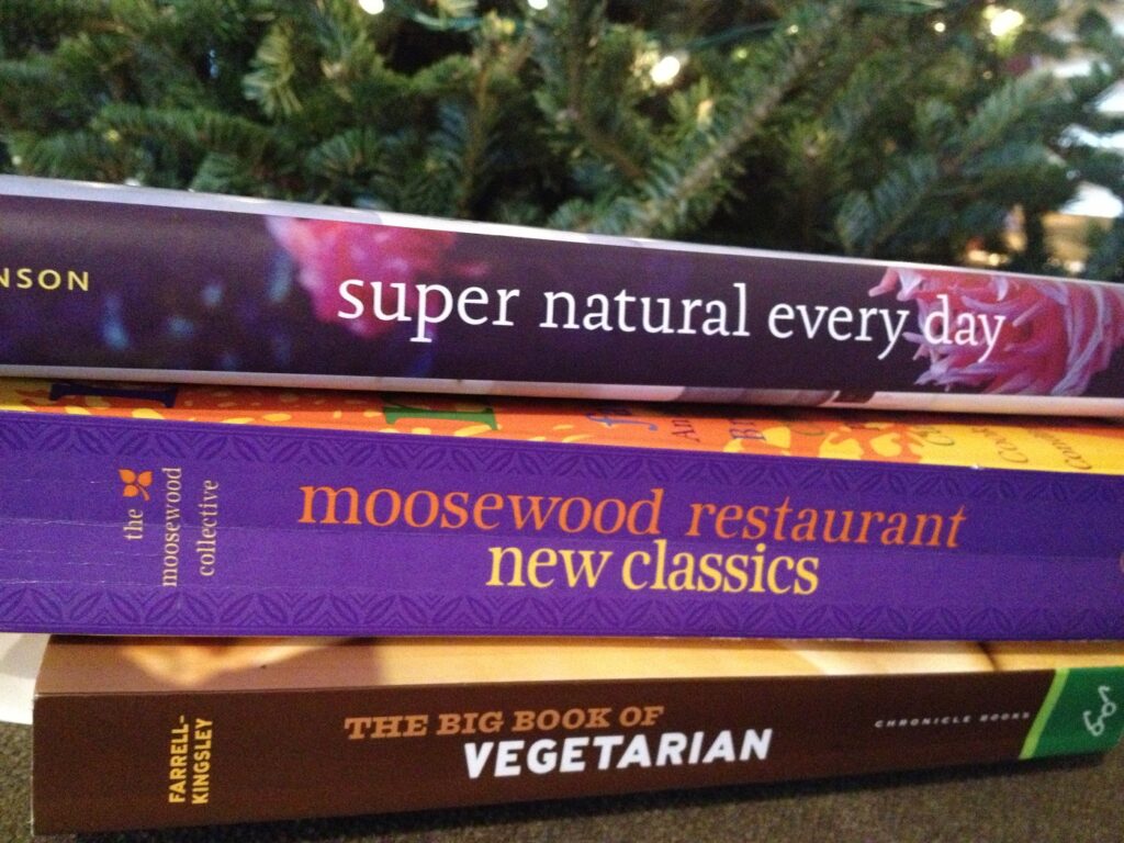 Stack of cookbooks in front of a Christmas tree