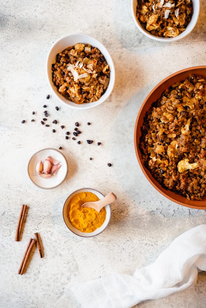 Top down view of a skillet of lentils and two servings in bowls