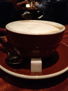 Cup of cappuccino with a sugar cube and spoon