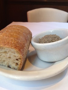 Small loaf of bread on plate with a cup of lentil spread