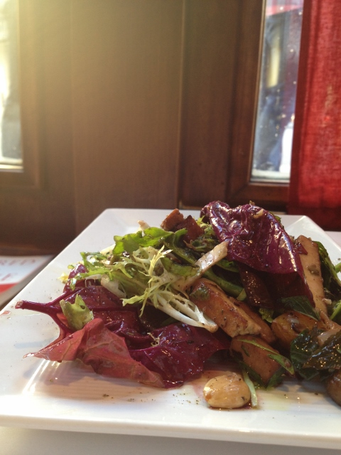 Spinach, tofu, potato and almond salad on a white plate