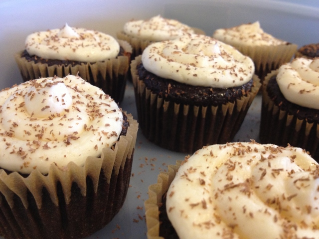 6 chocolate cupcakes with white frosting and chocolate shavings