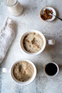 Top down view of two cups of soymilk with molasses, a napkin, and some molasses