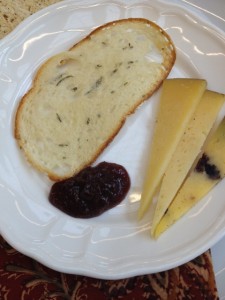 Bread, sliced cheese and a blob of jam on a white plate