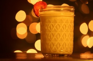 Strawberry milk in a small canning jar garnished with a freeze-dried strawberry in front of a Christmas tree