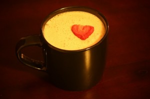 Strawberry milk in a dark cup garnished with a freeze-dried strawberry