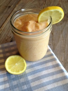 Peach smoothie in mason jar with sliced lemon garnish