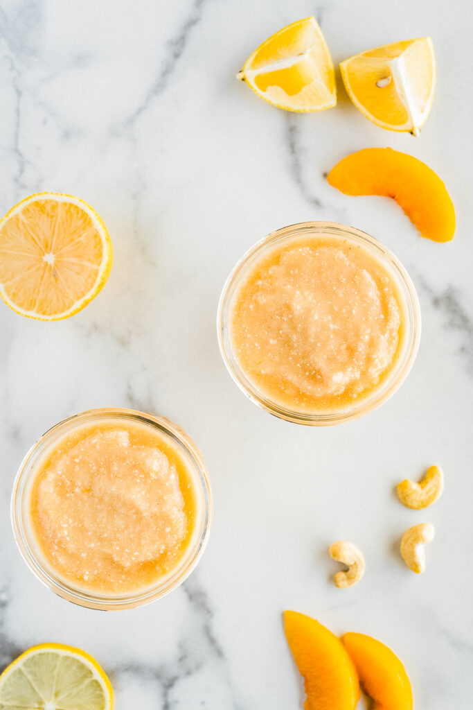 Top down view of two glasses of smoothie, cashews and peach slices