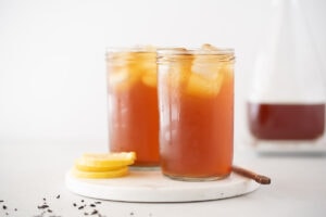 Two glasses of iced tea next to a bottle of tea