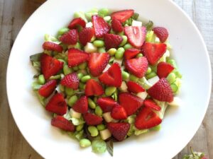 White bowl filled with lettuce, edamame beans and strawberries