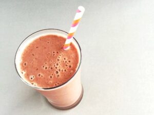 tall glass filled with cherry smoothie and a striped straw