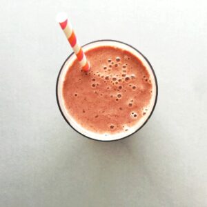 Top down view of cherry smoothie in a glass with straw