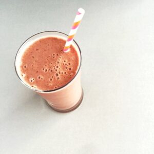 Top down view of glass with cherry smoothie and straw