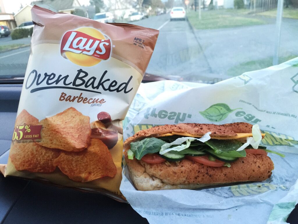 Subway sandwich and chips on car dashboard