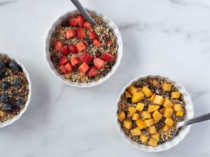 Top down view of 3 bowls of cereal with fruit