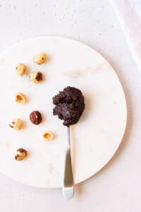 Spoonful of homemade nutella next to some hazelnuts
