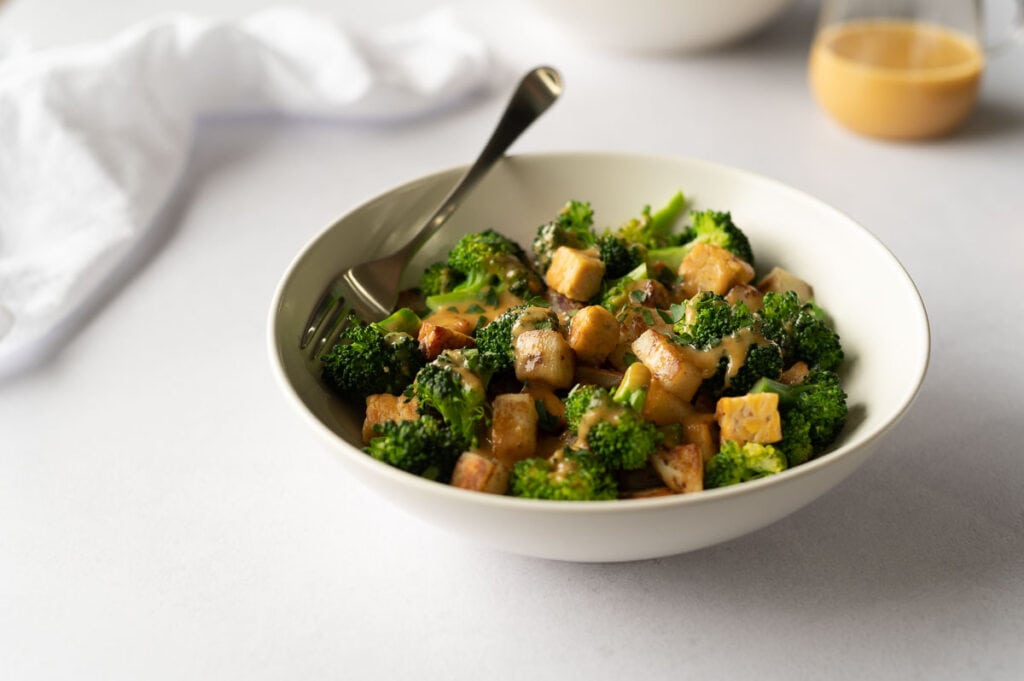 White bowl filled with broccoli, potatoes and tempeh