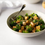 White bowl filled with broccoli, potatoes and tempeh