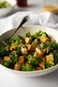 Close up side view of white bowl filled with veggies and tempeh