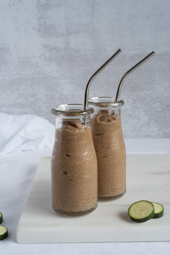 Two small jars full of chocolate smoothie with straws