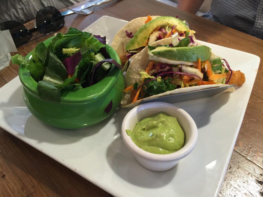 Bowl of salad alongside two vegetarian fish tacos