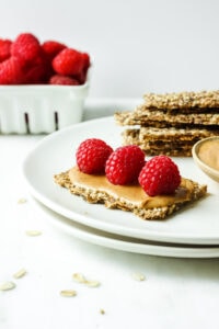 Plate with crackers, topped with peanut butter and raspberries
