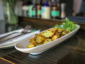 An oblong plate filled with roasted potatoes on a bar