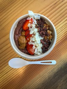 A small smoothie bowl photographed from the top down covered in cacao nibs, strawberries and coconut