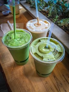 Three plastic cups filled with colorful smoothies