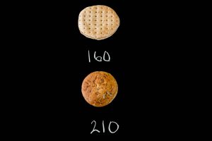 A sandwich thin and a hamburger bun on a black background with their calories listed (160, 210)