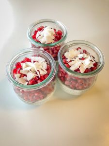 3 small Weck jars filled with chia pudding and topped with pomegranate and coconut