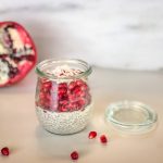 Small Weck jar with chia pudding and pomegranate in front of a cut pomegranate
